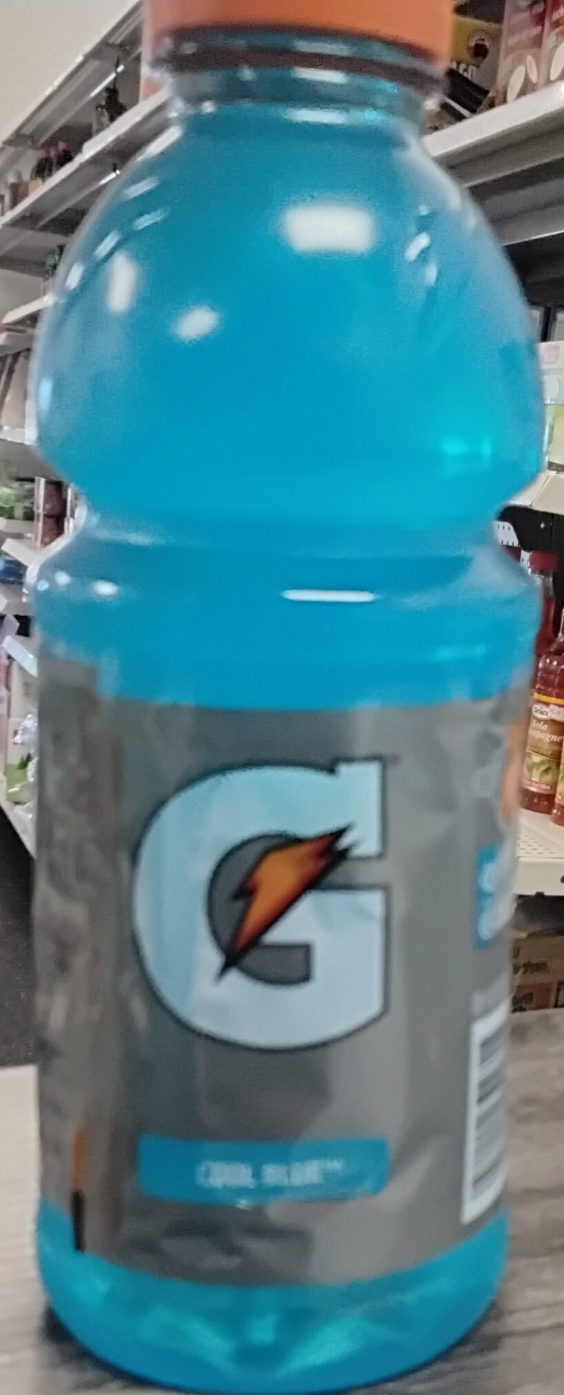 A 20 oz bottle of Gatorade Cool Blue by TOJ EXPRESS offers refreshing electrolyte hydration on a grocery shelf, with other products in the background.