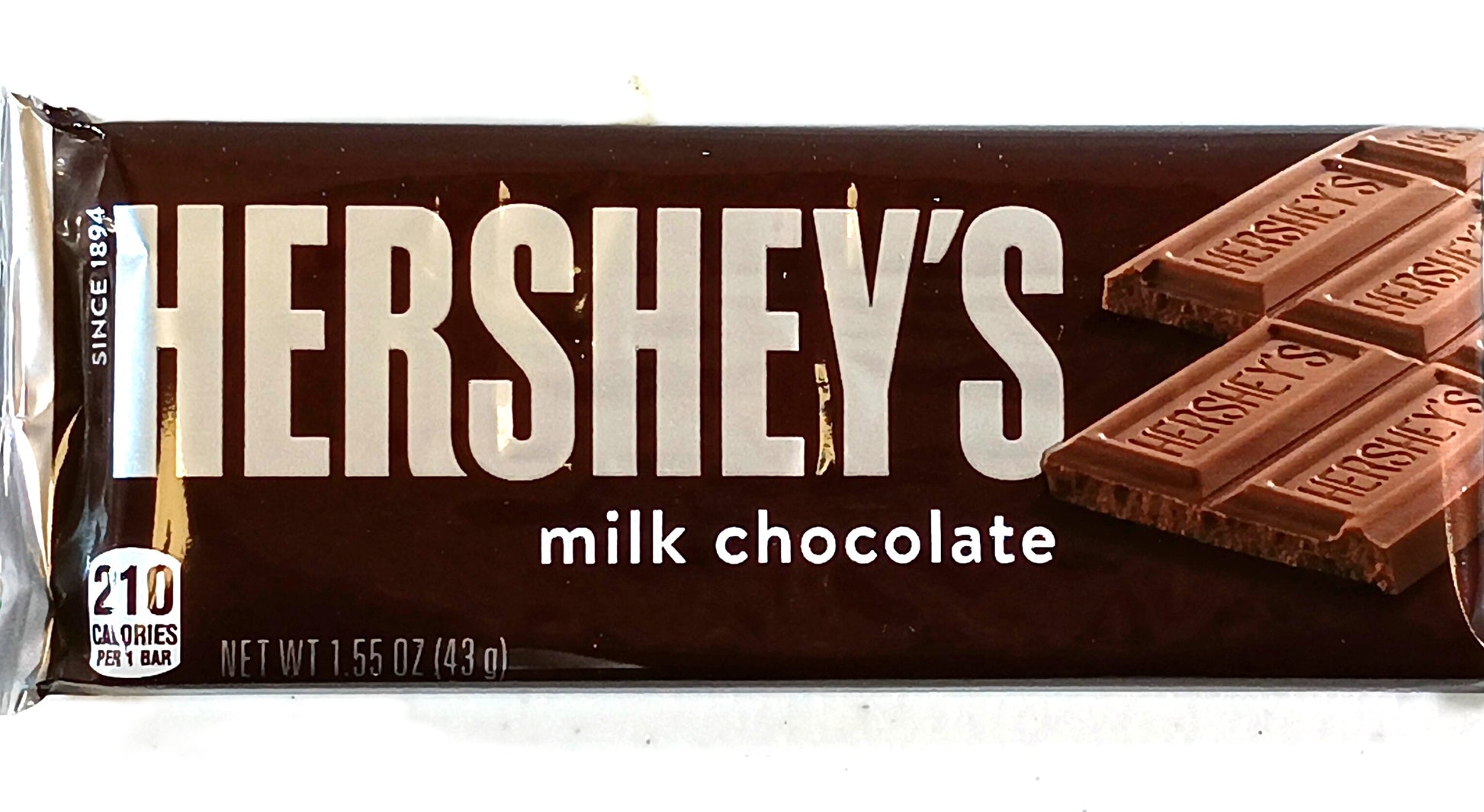 The TOJ EXPRESS Hersheys Chocolate Bar wrapper prominently features its famous logo and an image of chocolate squares. Made with premium cocoa beans for a creamy taste, this 1.55 oz (43g) treat contains 210 calories per serving.