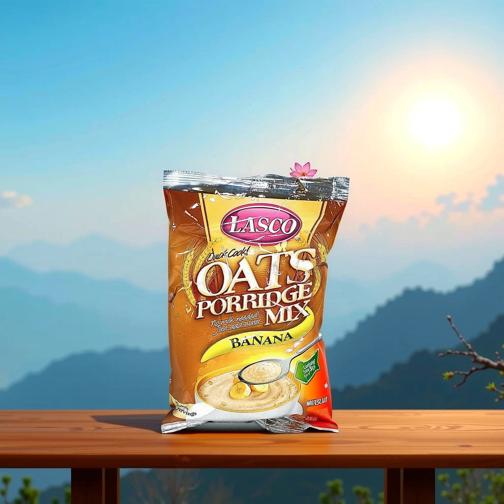 A TOJ EXPRESS Lasco Oats Porridge Mix packet rests on a wooden table against a sunrise mountain backdrop, featuring a porridge bowl with banana slices and cinnamon, emphasizing its rich banana flavor.