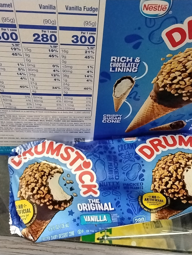 A partially opened TOJ EXPRESS DrumStick Ice Cream Vanilla cone sits before a box displaying nutrition facts and an image of the crispy cone with chocolate coating and peanuts.
