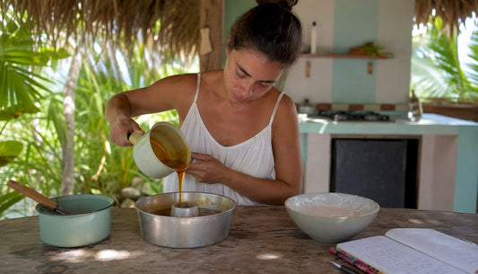 Woman pouring caramel into flan mold in kitchen