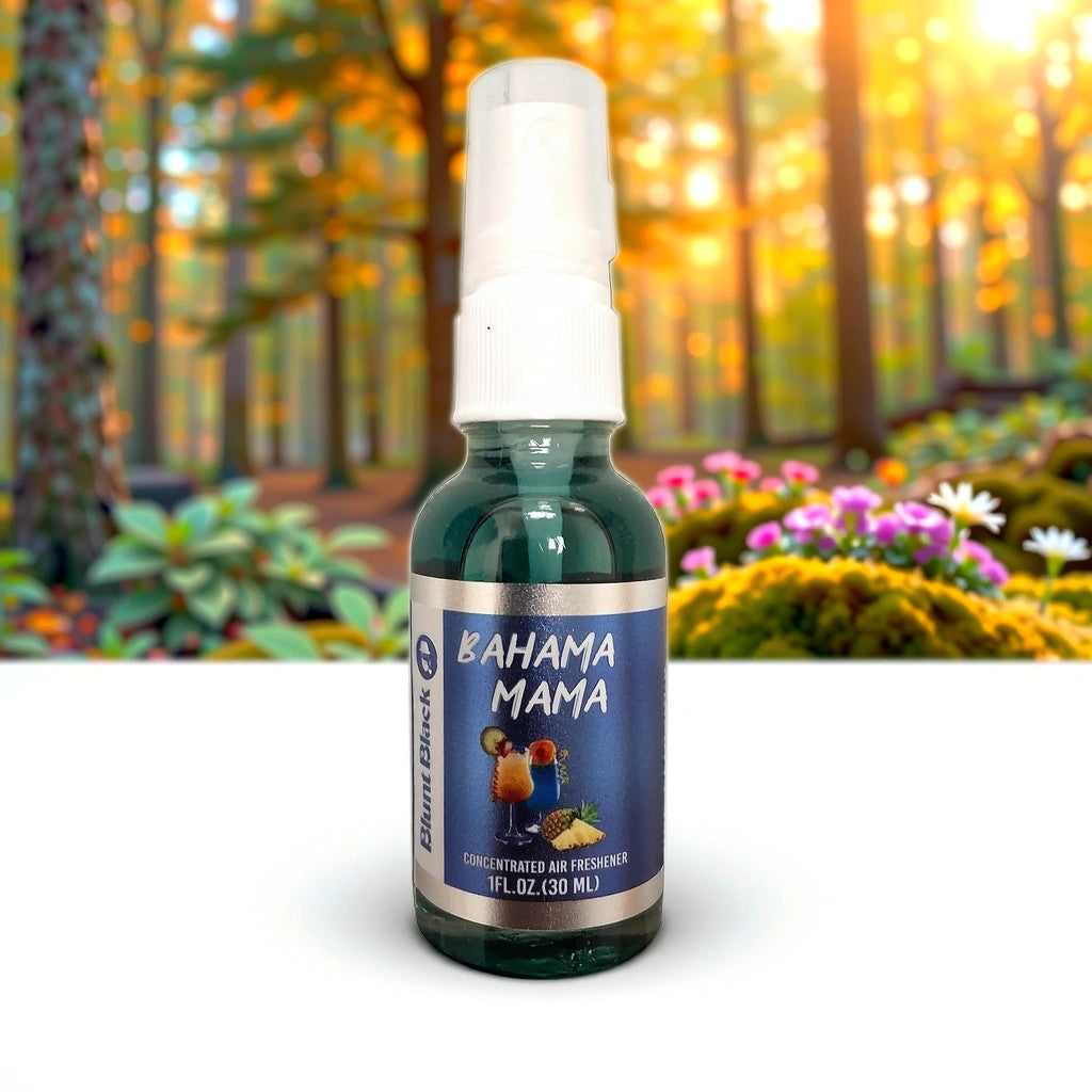 A small spray bottle labeled Bahama Mama air freshener stands on a white surface, with a blurred forest and flowers in the background. The bottle contains 1 fl. oz. (30 ml).