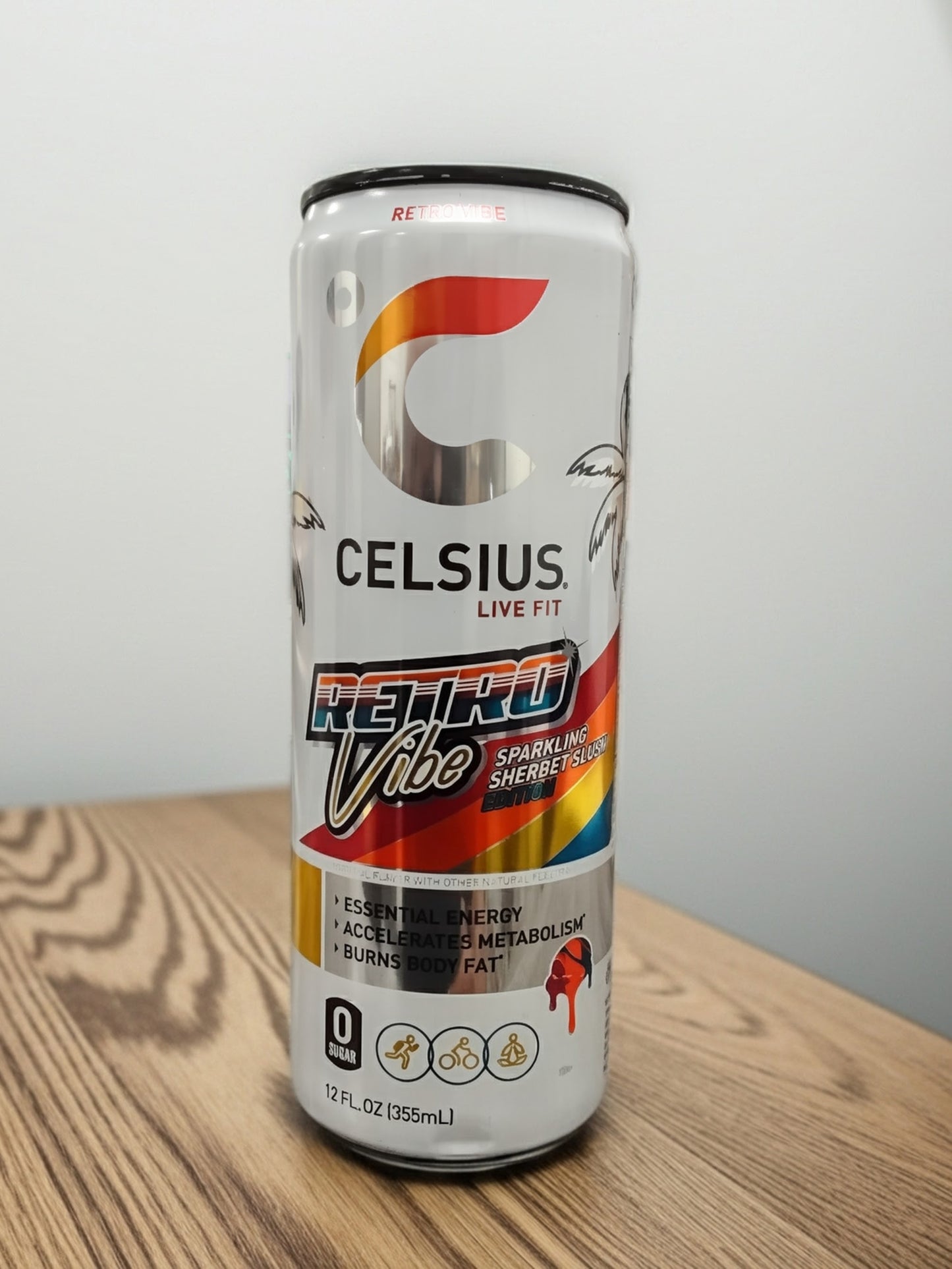 A 12 fl oz can of TOJ EXPRESS Celsius Retro Vibe energy drink rests on a wooden surface, featuring vibrant graphics and benefits such as essential energy, accelerated metabolism, and zero sugar—your ideal fitness companion.