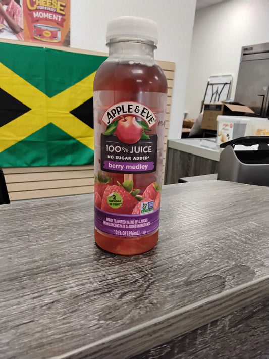 A bottle of TOJ EXPRESS Apple & Eve Berry Medley sits on a counter, with part of a Jamaican flag and a refrigerator visible in the background.