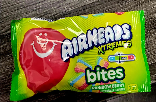 A green and yellow bag of RAINBOW BERRY Airheads Xtremes Bites by TOJ EXPRESS features colorful candy pieces, a smiling red mascot, “Sour,” and “250 calories” labels on the packaging.
