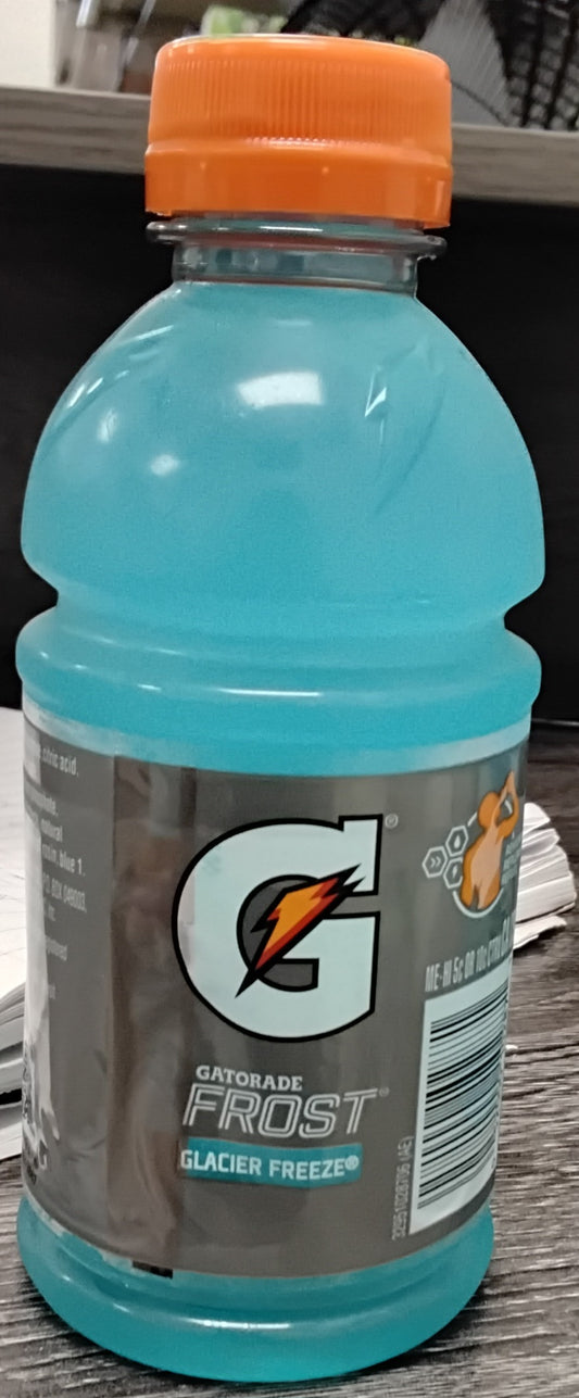 A 12 oz bottle of TOJ EXPRESS Gatorade Glacier Freeze with an orange cap rests on a dark wooden surface, displaying the Gatorade logo and nutritional info on its label.