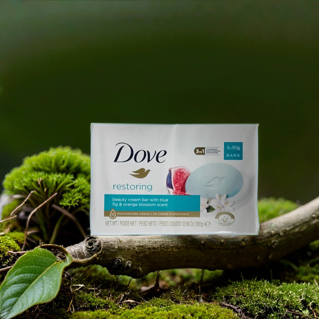 A TOJ EXPRESS Dove Bar Soap (restoring) with fig and orange blossom scent rests on a mossy tree branch among green leaves outdoors, emphasizing its gentle, natural skin-restoring properties.