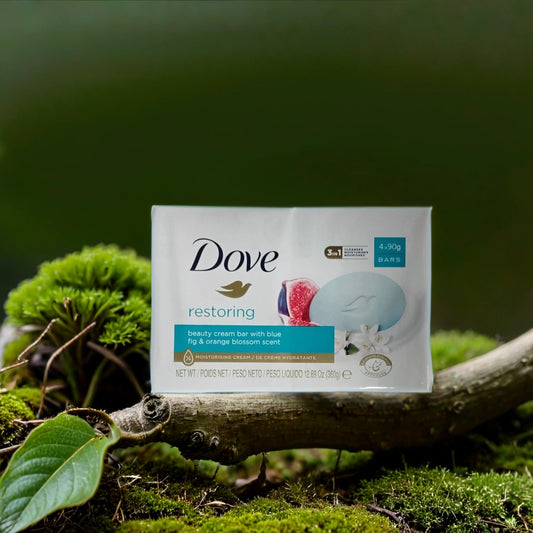 A TOJ EXPRESS Dove Bar Soap (restoring) with fig and orange blossom scent rests on a mossy tree branch among green leaves outdoors, emphasizing its gentle, natural skin-restoring properties.