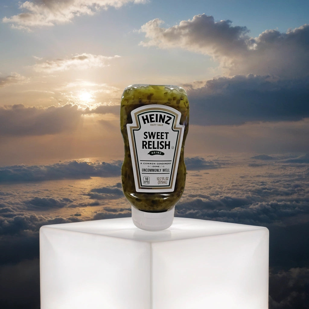A bottle of TOJ EXPRESS Heinz Sweet Relish sits on a glowing white cube, its vivid color highlighted against a dramatic sunset sky with clouds in the background.