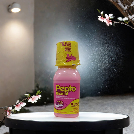 A 3.4 oz Pepto Bismal bottle by TOJ EXPRESS stands on a round table outdoors at night, encircled by blossoming branches and snow, brightly lit in the background—ready to soothe upset stomachs anytime.