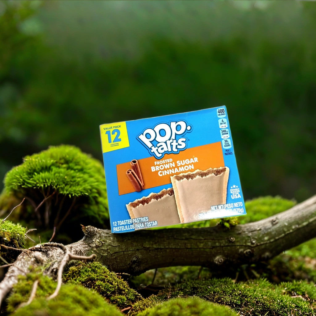 A box of TOJ EXPRESS Pop Tarts-Frosted Brown Sugar Cinnamon (12ct), the perfect breakfast snack, rests on a mossy log amid lush greenery and blurred foliage outdoors.