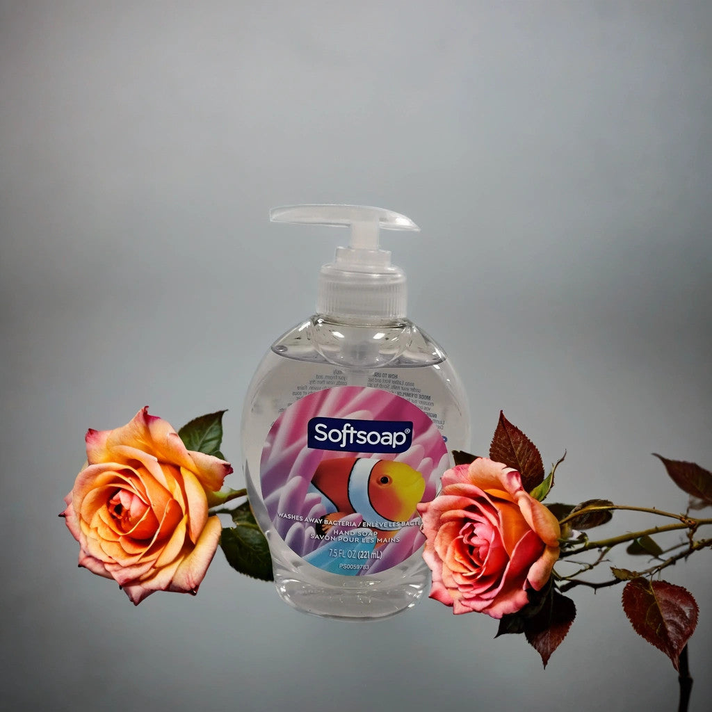 A bottle of TOJ EXPRESS Softsoap liquid hand soap sits between pink and yellow roses with green leaves on a plain light gray background.