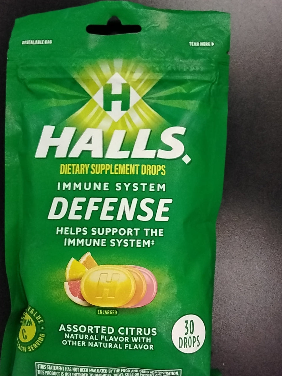 A green pack of TOJ EXPRESS Halls IMMUNE DEFENSE DROPS 30 CT, assorted citrus flavor, showing drops and fruit slices. Contains 30 drops and supports immune health and wellness.