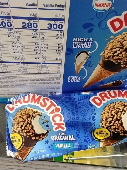 A partially opened TOJ EXPRESS DrumStick Ice Cream Vanilla cone sits before a box displaying nutrition facts and an image of the crispy cone with chocolate coating and peanuts.