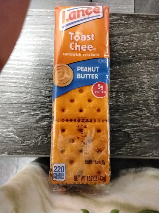 A pack of TOJ EXPRESS Lance Sandwich Crackers-Toast Chee w Peanut Butter rests on a wooden surface. Each 1.52 oz (43g) pack offers a tasty snack with 5g protein and 220 calories.