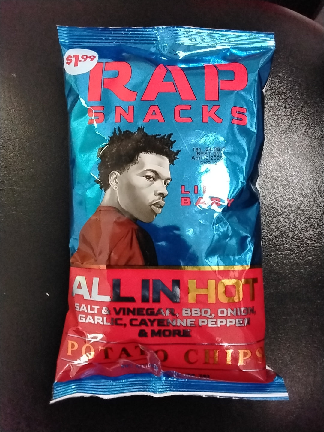 A blue TOJ EXPRESS RapSnacks-Salt & Vinegar bag features a cartoon man, Lil Baby. The $1.99 chips mix salt & vinegar, BBQ, onion, garlic, and cayenne for a bold flavor blend.