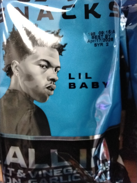 A close-up of a TOJ EXPRESS RapSnacks-Lil Baby Salt & Vinegar BBQ ONION GARLIC & MORE bag shows rapper Lil Baby in black and white on a blue background, “LIL BABY” beside him, and a Best By: April 7, 2026 date above the bold flavor snack.